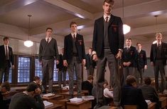 a group of men standing on top of desks in front of a class room