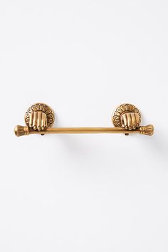 an antique gold toilet paper holder on a white wall with two hands holding the handle