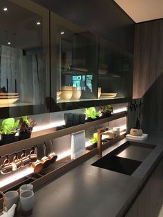 a kitchen counter topped with lots of pots and pans filled with plants on top of it