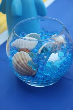 a bowl filled with blue sea glass and shells