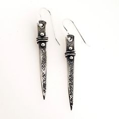 two pairs of silver earrings with black and white designs