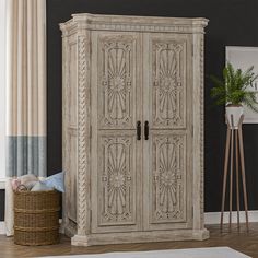 a white armoire sitting next to a basket on top of a wooden floor in front of a window