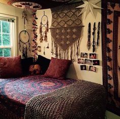 a bed with lots of pillows and pictures hanging on the wall next to a window