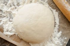 a ball of dough sitting on top of a piece of paper next to a rolling pin