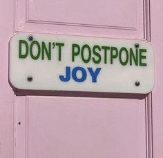 a sign that says don't postpone joy hanging on the side of a door