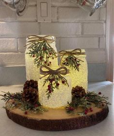 a lighted cake decorated with pine cones, berries and evergreens on a wooden slice