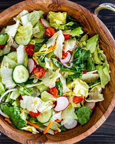 a salad with lettuce, tomatoes and cucumbers in a wooden bowl