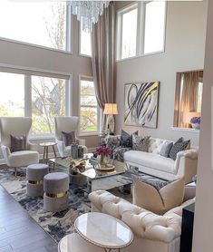 a living room filled with lots of furniture next to large window covered in curtains and chandelier