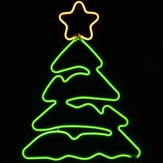 a neon green christmas tree with a star on top is lit up in the dark