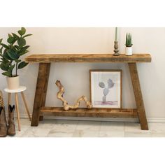 a wooden table with some plants and pictures on the shelf next to it in front of a potted plant