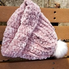 a pink blanket sitting on top of a wooden bench next to a white fur ball