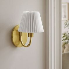 a wall light that is on the side of a white wall with a lamp shade