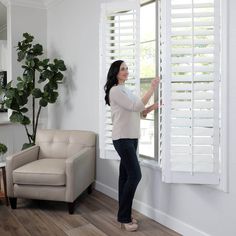 a woman opening the blinds in her living room