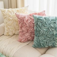 three decorative pillows sitting on top of a couch