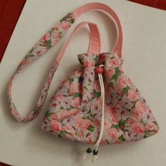 Pink Floral Drawstring Shoulder Pouch The pattern has pink flowers and green leaves on a pink background. The bag closes with a white cord through grommets and ends with one red and 2 green wooden beads. The bag closes with a drawstring and a snap at the top. The lining is all pink. There is one long cloth strap in pink and the pink flower pattern. The bag measures 9 x 3 x 10". Pink Rectangular Bucket Bag As Gift, Pink Rectangular Bucket Bag For Gift, Casual Pink Pouch Bucket Bag, Casual Pink Shoulder Bag For Gift, Casual Pink Shoulder Bag As Gift, Casual Pink Shoulder Bag Perfect For Gift, Pink Adjustable Bag, Pink Adjustable Shoulder Bag For Daily Use, Casual Handmade Pink Bucket Bag