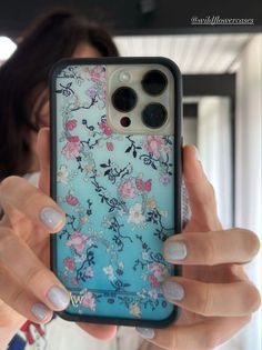 a woman holding up her phone case with flowers on it