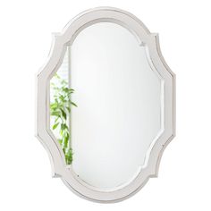 a white mirror sitting on top of a wall next to a potted green plant