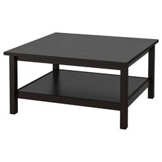 a black coffee table sitting on top of a white floor next to a wooden shelf