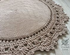 a crocheted doily is laying on the floor next to a wooden table