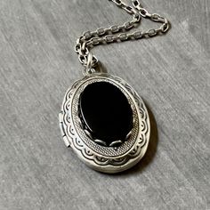 Antique Silver Onyx Locket Necklace....  This locket necklace is beautiful!  The locket is made of brass and is antique silver plated.  To the center of the locket, I added a flat top oval black onyx cabochon that sits in an antiqued silver brass setting. The high quality chain has soldered links and is non tarnish.  The chain closes with a lobster claw clasp.         Locket - 29mm height x 22mm width approximately Interior photo area - 20mm x 15mm wide approximately Chain - 24 inches long This Photo Area, Locket Necklace Vintage, Interior Photo, Necklace Vintage, Locket Necklace, Mother's Day Gift, Black Onyx, Lobster Claw, Locket