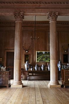 a large room with wooden floors and pillars in the center is filled with vases