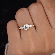 a woman's hand with a three stone diamond ring on top of her finger