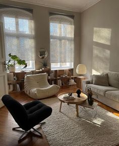 a living room filled with furniture and windows covered in shades of greys, white and neutrals