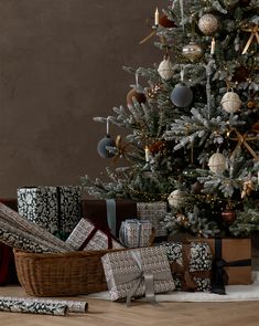 a christmas tree with presents under it in front of a pile of wrapped gift boxes