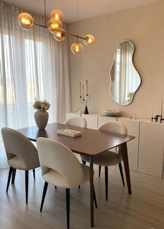 a dining room table with four chairs and a mirror on the wall in front of it