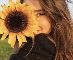 a woman holding a sunflower up to her face