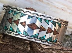 Vintage substantial and wide Navajo hand-stamped, artisan made. coral and turquoise chip inlay cuff bracelet. Classic Navajo geometric design. Handsome piece.  Light scratches and wear commensurate with age and use. Please refer to photos. The cuff is one-inch wide and weighs 37.7 grams. The circumference is just shy of 5" and the gap is 1-7/8", for a total of 6-7/8" circumference. There is a word or name roughly etched into the metal, D. Partis?, as well as a number, 14346651. Hard to get a goo Southwestern Inlay Cuff Bracelet Gift, Handmade Southwestern Turquoise Cuff Bracelet, Southwestern Stamped Cuff Bracelet As Gift, Southwestern Stamped Cuff Bracelet For Gift, Artisan Turquoise Bracelets With Inlay, Artisan Turquoise Bracelet With Inlay, Southwestern Style Turquoise Inlay Bracelets, Artisan Multicolor Cuff Bracelet With Inlay, Southwestern Turquoise Inlay Bracelet