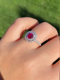 The Titania Double Halo Ruby and Diamond Ring in 14 Karat White Gold. This contemporary cocktail ring centers on a 1.05 carat ruby. The ruby is encircled by a double diamond halo with diamonds continuing down either side of the shank. The mounting has 0.58 total carats of diamonds. This modern ring is a finger size 6 3/4, yet can be adjusted to any size. Each piece has been hand selected and meticulously identified and graded by a Graduate Gemologist who has been awarded a degree by the Gemologi Gia Certified Round Cut Ruby Ring Fine Jewelry, Ruby Ring With Brilliant Cut Diamond, Brilliant Cut Diamond Ruby Ring, Gia Certified Round Cut Ruby Ring, Round Brilliant Cut Ruby Ring With Diamonds, Fine Jewelry Ruby Ring With Round Cut Diamond, Brilliant Cut Ruby Ring With Diamonds, Dazzling Gia Certified Ruby Ring, Luxury Ruby Diamond Ring With Halo