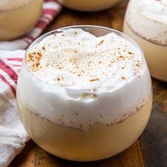 two glasses filled with dessert sitting on top of a wooden table