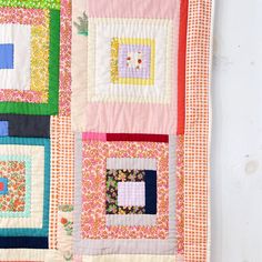 a quilted wall hanging on the side of a white door with colorful squares and flowers