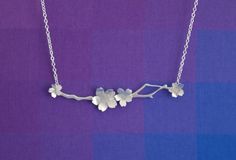 This handcrafted Japanese cherry blossom necklace is a delicate, feminine necklace that is perfect for everyday wear. This expertly handmade silver branch features 4 delicate sterling silver cherry blossoms. This necklace is a great way to celebrate spring all year long.  This necklace is 18" long, hanging from a sterling silver chain.  Get the earrings and necklace set and save!: https://www.etsy.com/listing/495634401/silver-sakura-necklace-and-earring-set Matching Silver Japanese Cherry Blosso Elegant Blossom Necklace With Flower Charm, Japanese Necklace Traditional, Sakura Necklace, Sakura Flower Jewelry, Blossom Colored Flower-shaped Sterling Silver Jewelry, Cherry Blossom Necklace, Feminine Necklace, Dogwood Flowers, Japanese Cherry Blossom