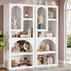 a white book shelf filled with books next to a plant and vase on top of a hard wood floor