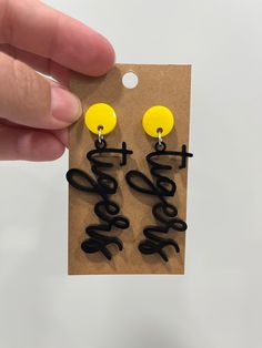 a pair of black and yellow earrings with the word love written on it in cursive writing