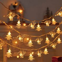 a string of christmas lights with angels and bells hanging from the strings in front of a fireplace