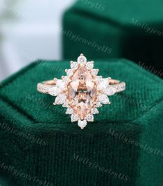 an engagement ring with a pink diamond surrounded by white and rose cut diamonds in a green velvet box