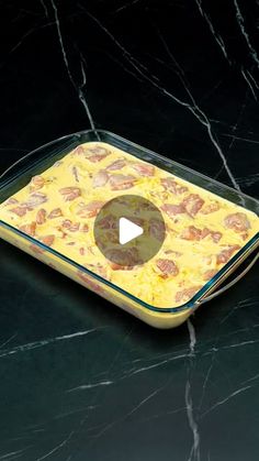 a glass dish with food in it on a black counter top next to a knife