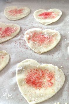 heart shaped pastries on a baking sheet with sprinkles and powdered sugar