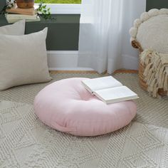 a pink bean bag chair sitting in front of a window with a book on it