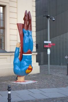 a large blue and red sculpture sitting on top of a sidewalk next to a tall building