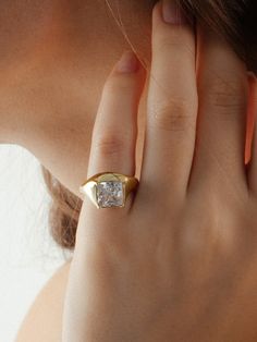 a woman wearing a gold ring with a princess cut diamond on it's side