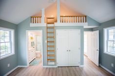 a loft with stairs leading to the top floor and two windows on either side of the room