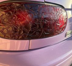 the rear end of a purple car with flowers etched on it's side window