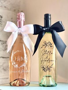 two personalized wine bottles tied to each other with a bow on the top one