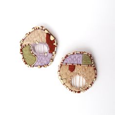 two wooden buttons with different colored designs on them, one has a hole in the middle