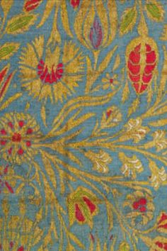 an old blue and yellow rug with red flowers on it