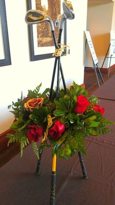 a bouquet of roses and golf clubs in a vase on a table with other decorations